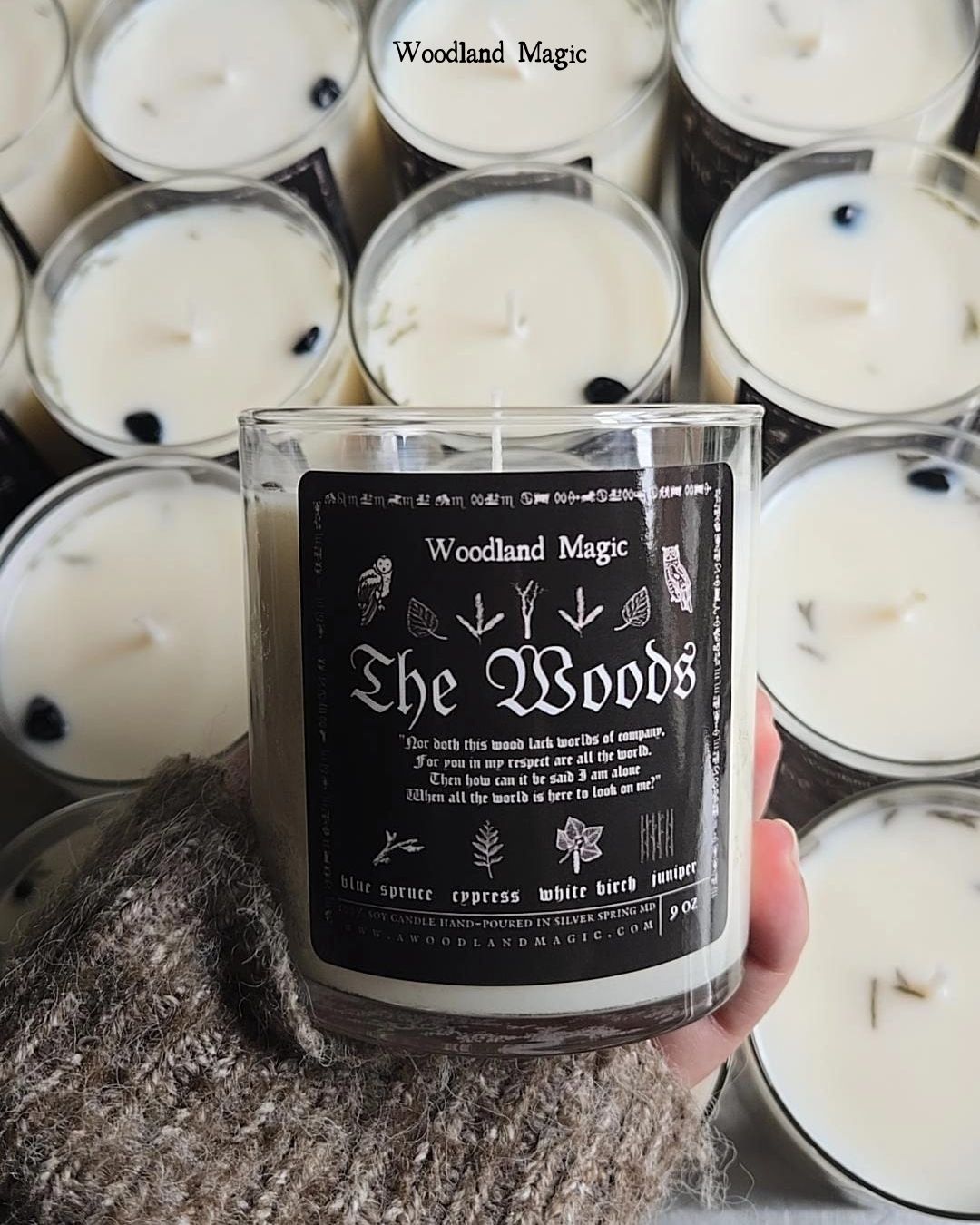 Candle with 'The Woods' label held in front of more candles